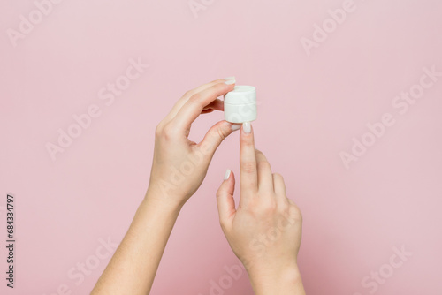 White jar or bottle with cream (ointment) in woman's hands. Facial care, bottle with cosmetic product © Anton Tolmachov