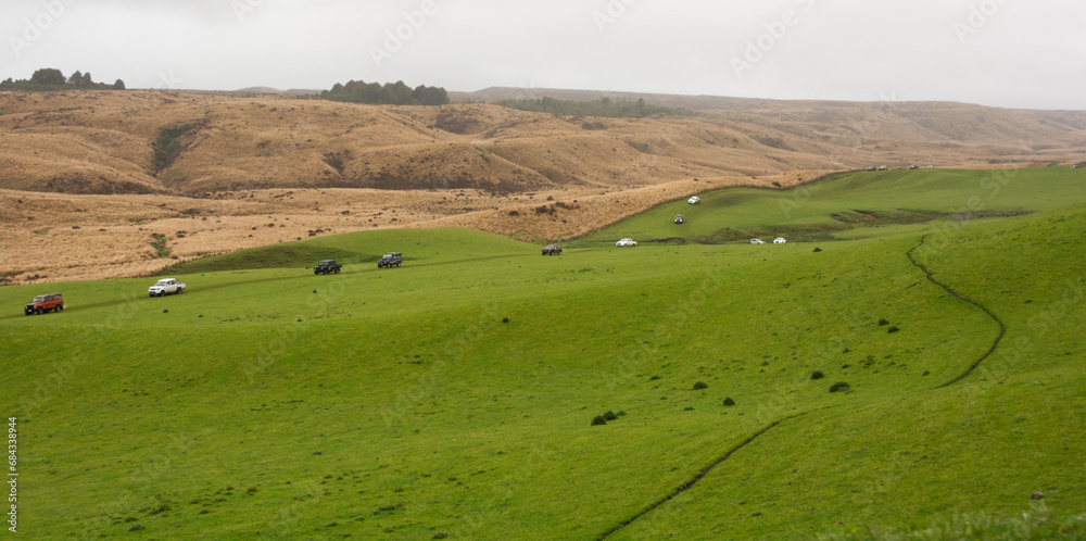 4WD vehicles in convoy cross high country farmland in New Zealand
