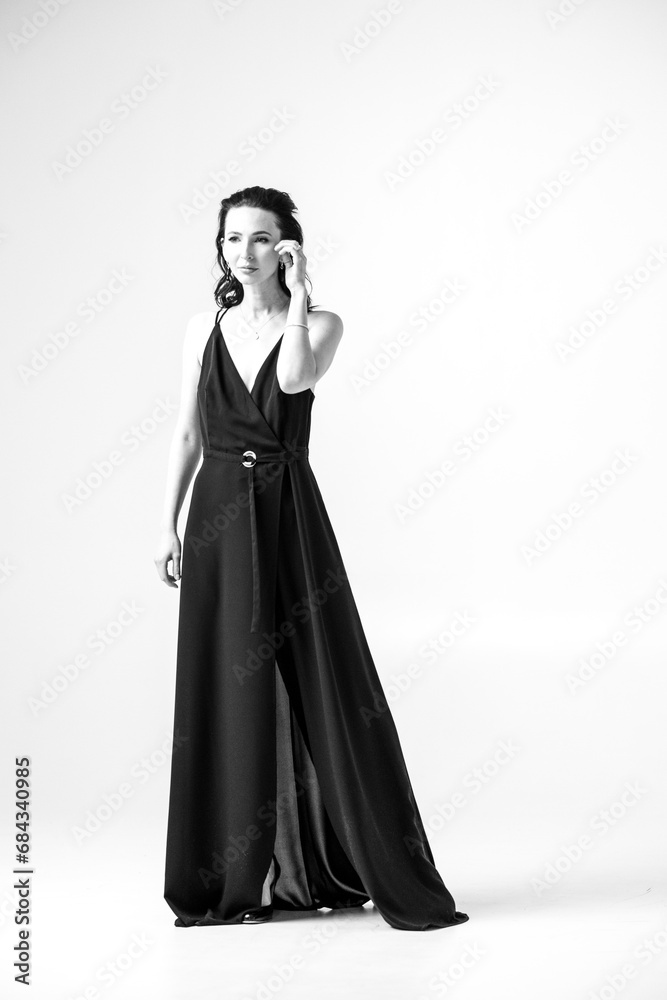 Fototapeta premium Beautiful black-haired woman, girl, in a black dress, on a white studio background