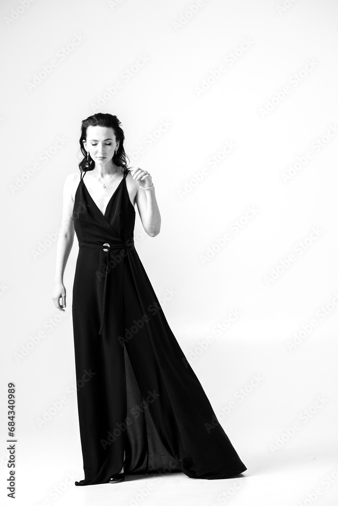 Beautiful black-haired woman, girl, in a black dress, on a white studio background Beautiful black-haired woman, girl, in a black dress, on a white studio background