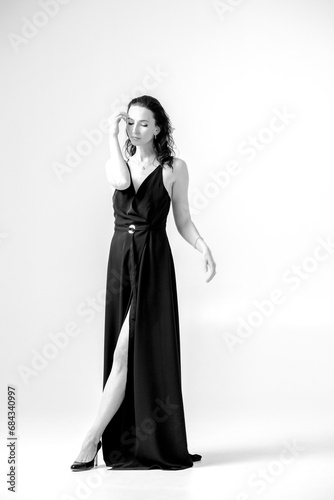 Beautiful black-haired woman, girl, in a black dress, on a white studio background