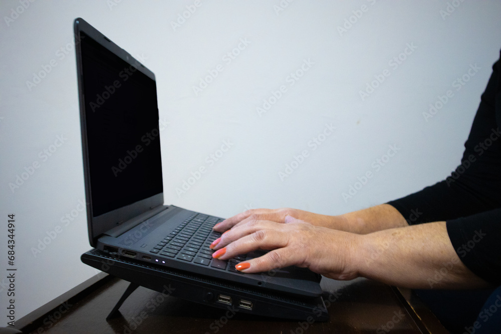 Female hands typing on a laptop with blank screen. Female hands typing on a laptop with blank screen.