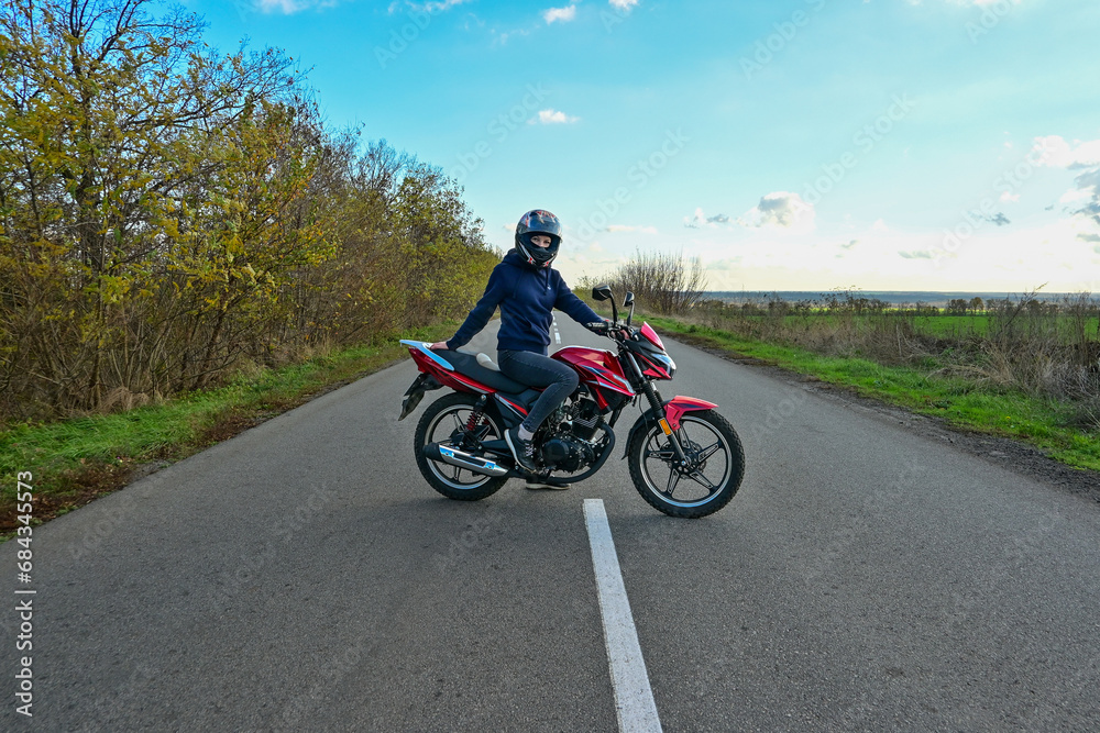 biker girl in a helmet sits on a motorcycle on the road.