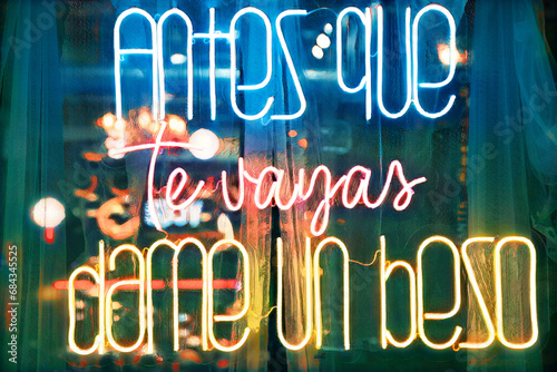 Love lettering on a mosaic background. Neon sign in the window of a cafe at night, Spanish