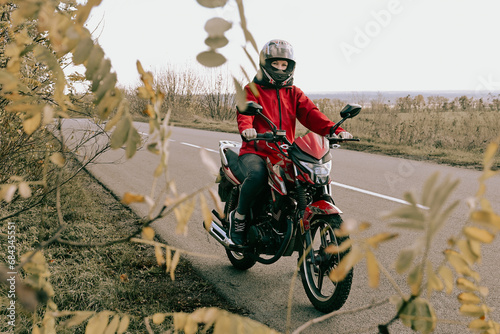 Biker girl on a motorcycle rides on an empty asphalt road outside the city.