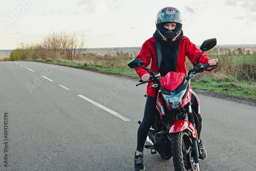 Biker girl on a motorcycle rides on an empty asphalt road