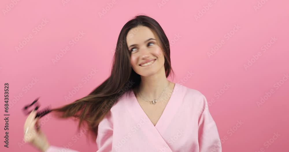 Lovely coquettish brunette woman, winking playfully, flirting. Woman fix her hair isolated on pink color. Brunette hair fashion model face smiling removes hair clipper and untangles hair. Lovely coquettish brunette woman, winking playfully, flirting. Woman fix her hair isolated on pink color. Brunette hair fashion model face smiling removes hair clipper and untangles hair.
