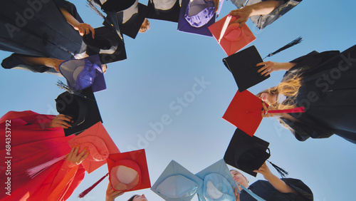College graduates make a circle shape out of their colorful hats.