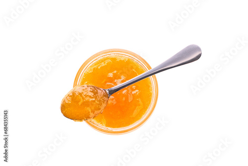 Top view of orange jam in jar with spoon isolated on white background.
