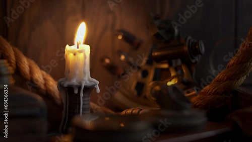 Antique burning candle with vintage sextant, rope and other marine accessories. Sea adventure concept. Selective focus, low shallow focus
