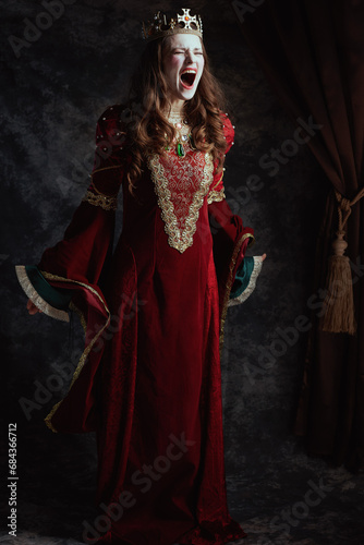 mad medieval queen in red dress with white makeup and crown