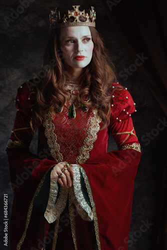 medieval queen in red dress with white makeup and crown
