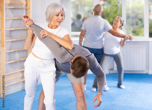 Aggressive old woman twisting her opponent's arm during self-defense classes