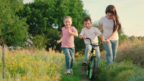 Active Mom teaches her little daughter, son to ride bike, sunset. Mother teaches her child to keep balance while on bicycle. Childhood dream of riding bike. Family life, mom, baby, parental support