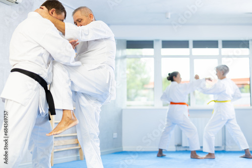 Dynamic photo capturing energy and focus of senior athletics students people fighting in aikido class. Obtaining black belt, advanced training, highest dan of martial arts. Sport to max.