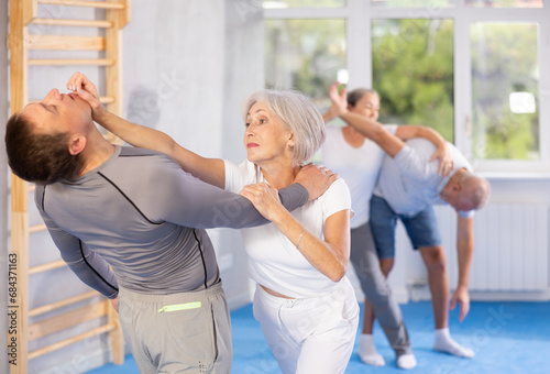 Elderly woman delivers painful blow to her eyes during a self-defense course in the gym © JackF