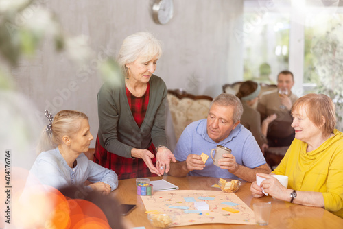Group of positive older people playing tabletop game
