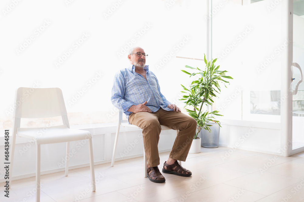 An older man waits in the reception area of a clinic for a rehabilitation and maintenance physiotherapy session An older man waits in the reception area of a clinic for a rehabilitation and maintenance physiotherapy session