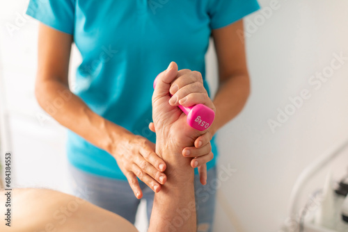 Canvas Print A physical therapist performs a manual therapy session with a weight to rehabili