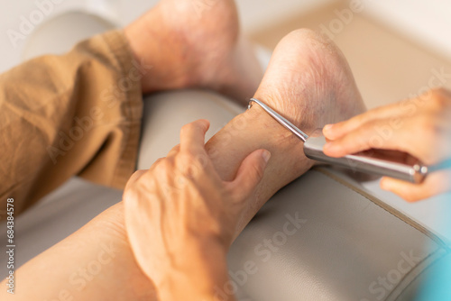 An older man is treated in a physiotherapy clinic with a hook and diacutaneous fibrolysis technique in the foot and ankle area