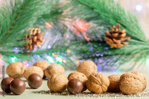 Walnuts and candies close-up on the background of Christmas tree branch with cones