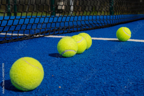 five paddle tennis balls close to the net of a paddle tennis court © Vic