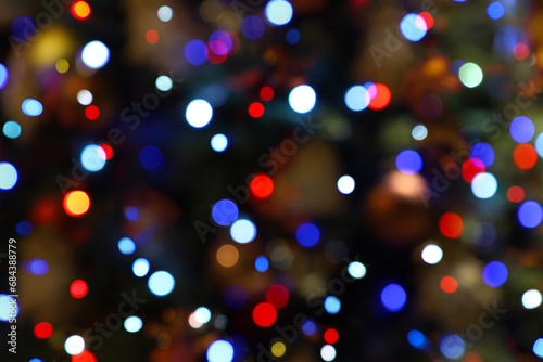 Colorful bokeh lights - big, small, blue, red. Abstract blurred Christmas tree garland lights background. Holiday New Year illumination and decoration concept. Defocused image.