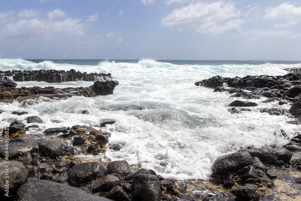 Powerful ocean waves crashing with violence on rocks. The sea meets the shore on the tropical island of Kauai, Hawaii during a storm with high wind. Powerful ocean waves crashing with violence on rocks. The sea meets the shore on the tropical island of Kauai, Hawaii during a storm with high wind.