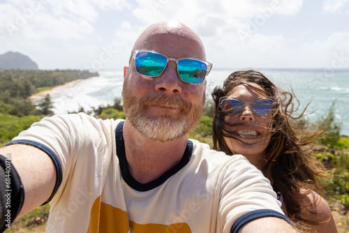 Happy middle aged couple together on vacation at ocean beach. The man and woman are smiling for a selfie overlooking the sea.  photo