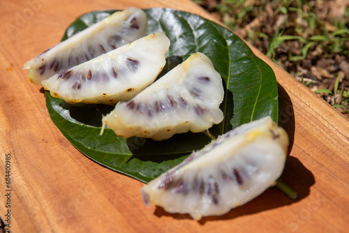 Fresh sliced noni fruit on a cutting board. The fruit has a pungent aroma like stinky cheese.  photo