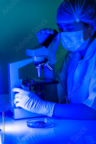 Vertical Scientist women in lab look at science microscope medical test researching biology chemistry with blue light black background. Male technician laboratory analyze Chemistry Medical research