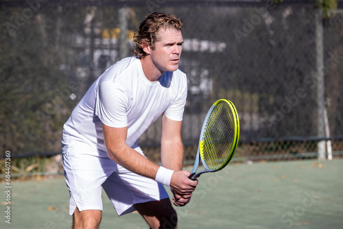 Athletic man on tennis court. The player is holding a racket or racquet in a match and his ready to compete.