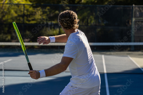 Athletic man on tennis court. The player is holding a racket or racquet in a match and his ready to compete. photo