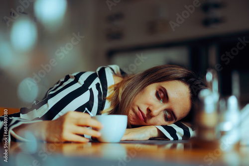 Tired Woman Sleeping with the Head on the Table. Exhausted lady having problems to stay awake with ought caffeine 
 photo