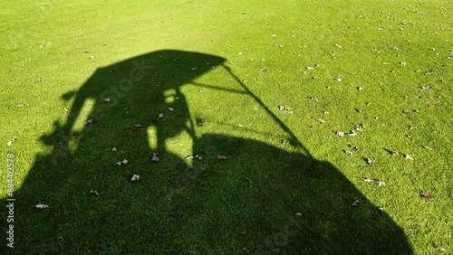 Shadow of a Golf Cart and a Golfer That Travel on the Green Grass and Leaves on the Fairway in a Sunny Day on the Golf Course in Switzerland