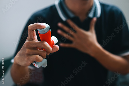 Man holding asthma inhaler for relief asthma attack.