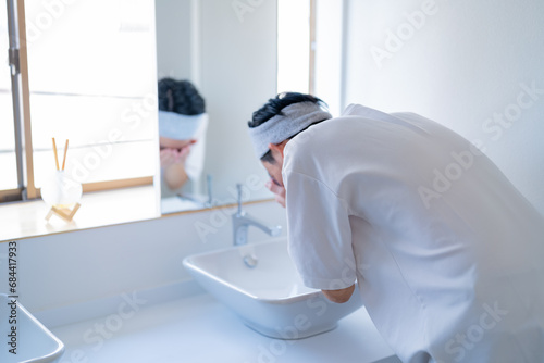 洗面台で顔を洗う若い日本人男性