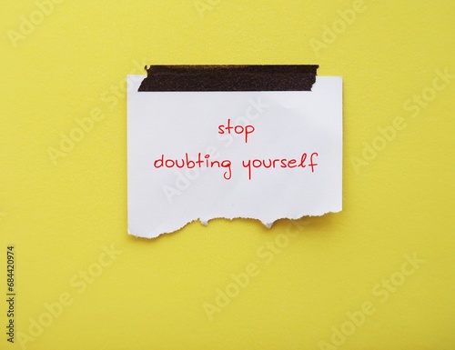 Note on yellow background with handwritten text STOP DOUBTING YOURSELF, concept of self-doubt, lack of confidence  mindset that holds back from succeeding leads to imposter syndrome or self sabotage