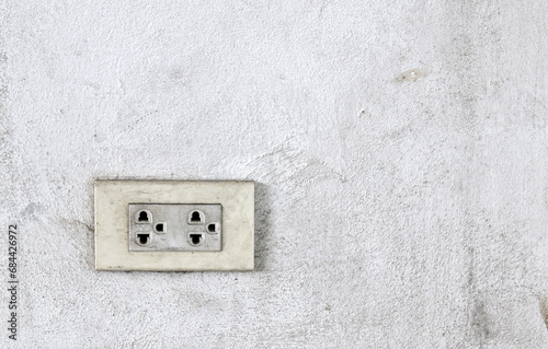 dirty electric outlet on grimy rough white concrete wall