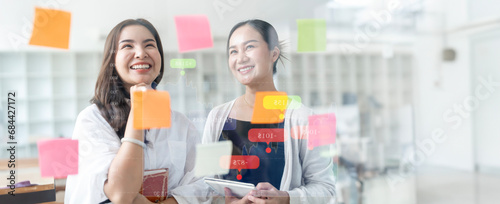Creative business woman brainstorming using sticky notes on glass wall in office.