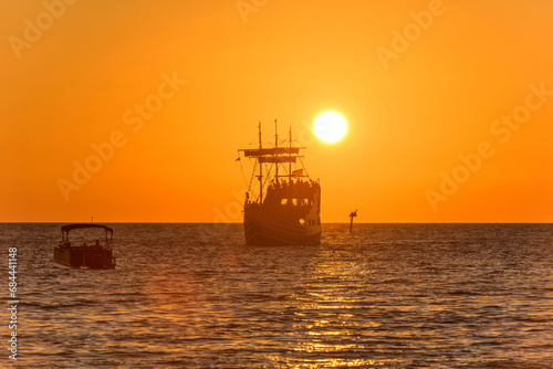 Golden Sunset - Tour boats sailing towards the setting sun and orange sky on a calm Autumn evening. Clearwater, Florida, USA. © Sean Xu