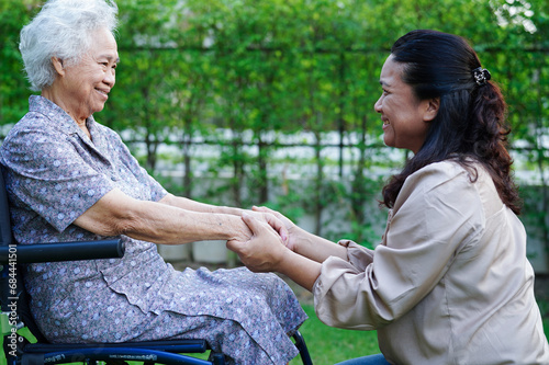 Caregiver help Asian elderly woman disability patient sitting on wheelchair in park, medical concept. © manassanant