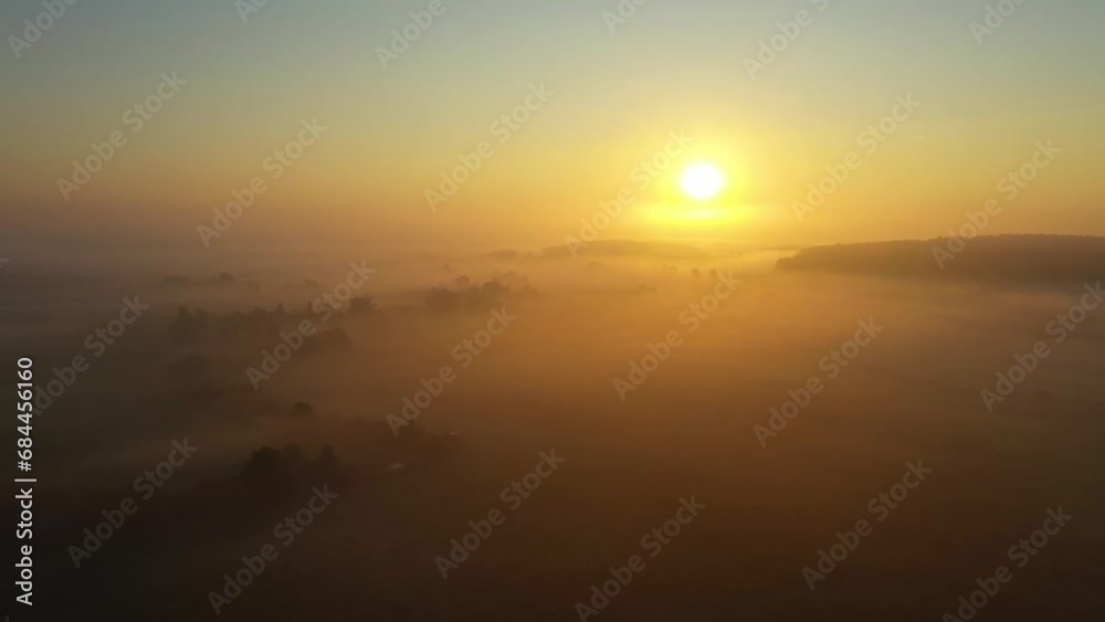 Fog morning over the plain and river floodplain of the meadow near a rural village with a house, aerial 4K view landscape. Flight over a typical German village in fog