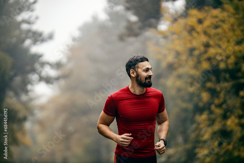 Portrait of a wet sportsman running in nature on foggy and rainy weather.