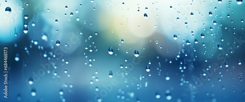 blue raindrops on a window pane, with a blurred blue landscape in the background.