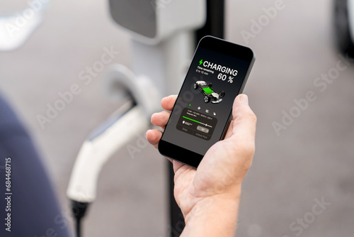 Fototapeta Naklejka Na Ścianę i Meble -  Man using smartphone online banking application to pay for electric car battery charging from EV charging station during vacation holiday road trip at national park or summer forest. Exalt