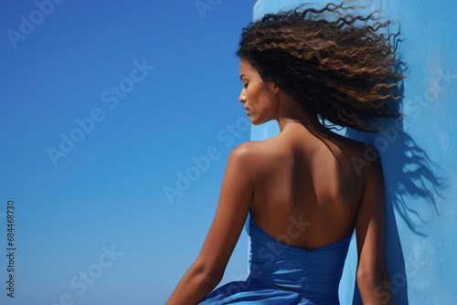 Graceful woman with dynamic Afro hairstyle against blue background