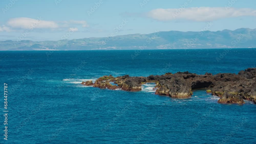 Wide shot of rocky coastline. calm blue ocean. Sunny day, clear sky. Wide shot of rocky coastline. calm blue ocean. Sunny day, clear sky.