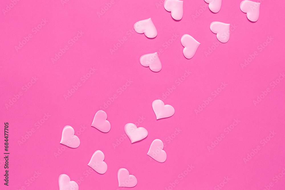 Pink silk hearts flat lay on a pink paper background. Top view. Valentine's Day card.