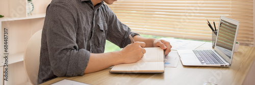 Man studies online on a laptop, Chat via laptop, Take notes, Learn online.